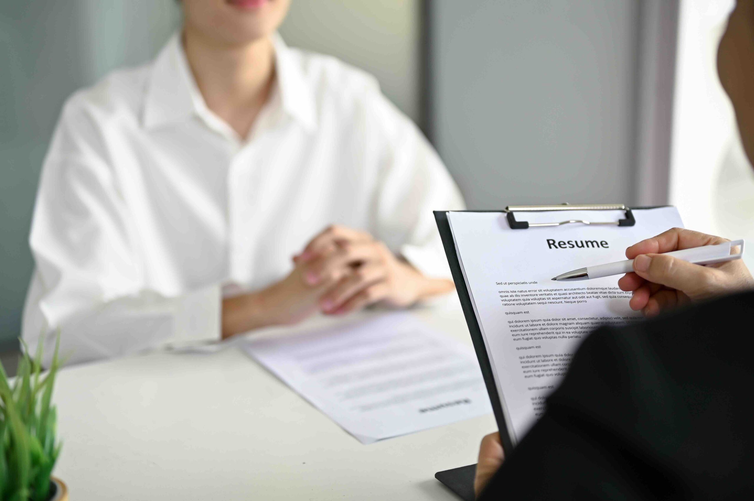 Close-up image of a professional recruiter or HR manager reading a candidate's resume during a job interview.